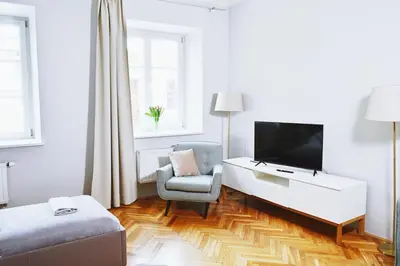 a white living room with a tv and a chair at 21 Floriańska Street Apartments in Kraków