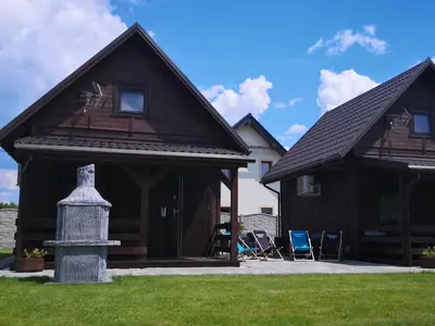a house with a porch with two chairs in the yard at Domki Całoroczne Danielowa Ostoja-Zator,Palczowice in Zator