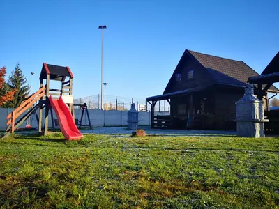 a playground with a red slide in a yard at Domki Całoroczne Danielowa Ostoja-Zator,Palczowice in Zator