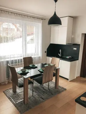 a dining room with a table and chairs and a kitchen at Jaszczurowa Apartament II in Jaszczurowa