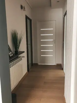a hallway with a white door and wooden floors at Jaszczurowa Apartament II in Jaszczurowa