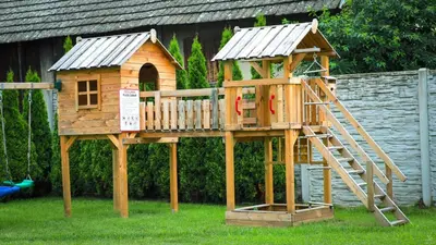 a wooden play house with a ladder in the grass at Calm Village in Zator