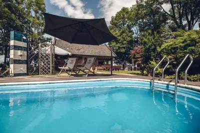 a swimming pool with an umbrella and two chairs at Kawalerski, Impreza, Wesele in Miechowice Wielkie