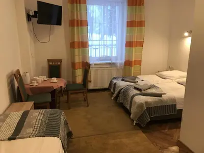 a room with two beds and a table and a window at Diablak in Zawoja
