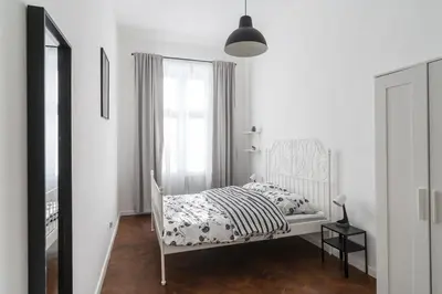 a white bedroom with a bed and a window at Podzamcze 24 Apartments in Kraków