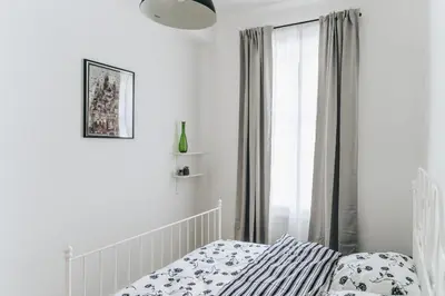 a white bedroom with a bed and a window at Podzamcze 24 Apartments in Kraków