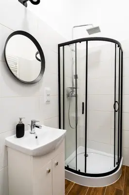 a bathroom with a shower with a sink and a mirror at Podzamcze 24 Apartments in Kraków