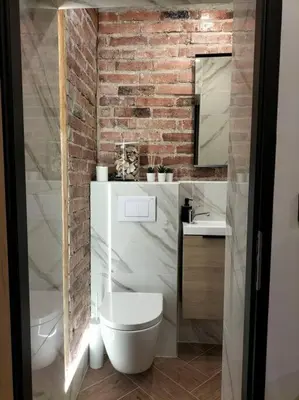 a bathroom with a white toilet and a brick wall at Uroczy apartament w centrum Krakowa in Kraków