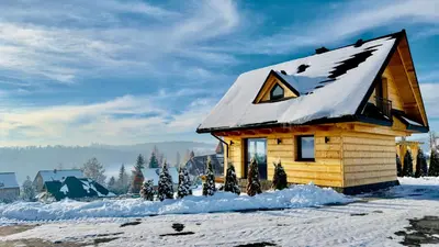 a log cabin with snow on the roof at Tatra Village in PyzÃ³wka