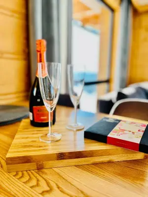 a bottle of wine and two glasses on a wooden table at Tatra Village in PyzÃ³wka