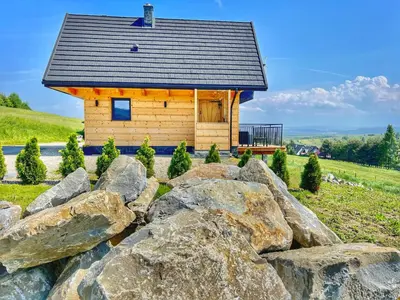 a log cabin behind a rock wall at Tatra Village in PyzÃ³wka