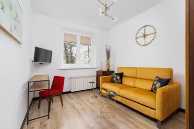 a living room with a yellow couch and a red chair at Apartments Osiedle Szkolne Cracow by Noclegi Renters in Kraków