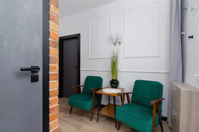 a dining room with two green chairs and a table at Apartments Osiedle Szkolne Cracow by Noclegi Renters in Kraków