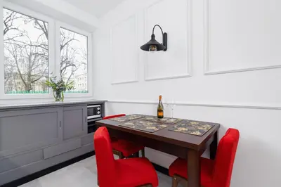 a kitchen with a wooden table and red chairs at Apartments Osiedle Szkolne Cracow by Noclegi Renters in Kraków