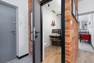 a brick wall and a door leading to a bathroom at Apartments Osiedle Szkolne Cracow by Noclegi Renters in Kraków