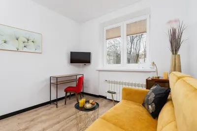 a living room with a yellow couch and a red chair at Apartments Osiedle Szkolne Cracow by Noclegi Renters in Kraków