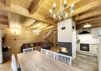 a kitchen and living room with a table and a fireplace at Willa Stryszawka in Stryszawa