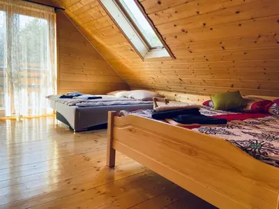 two beds in a room with a wooden wall at Willa Stryszawka in Stryszawa