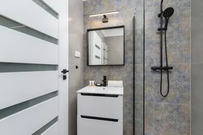 a bathroom with a shower with a sink and a mirror at Modern Studio Cracow Rakowicka 14 by Noclegi Renters in Kraków
