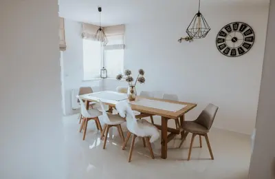 a dining room table with chairs and a clock on the wall at Wzgórze Marzeń in Zembrzyce