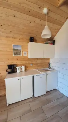 a kitchen with a table and a small kitchen with white appliances at Podbucznik 4 Polica in Targoszów