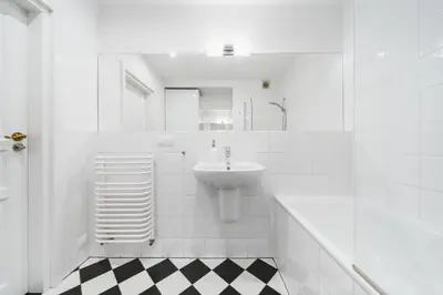 a white bathroom with a sink and a black and white checkered floor at In The Heart Of Jewish Quarter - Old Synagogue - by Upstairs in Kraków