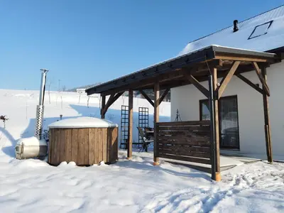 a white house with a black roof on a dirt road at KOCIA GÓRA in Chomranice