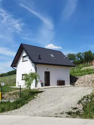 a small white house with a black roof at KOCIA GÓRA in Chomranice