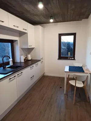 a kitchen with white cabinets and a table and a window at KOCIA GÓRA in Chomranice
