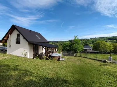 a white house with a black roof on a green field at KOCIA GÓRA in Chomranice