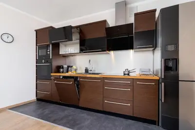 a kitchen with wooden cabinets and a black refrigerator at Dzielnica XIII Podgórze Kraków by Noclegi Renters in Kraków