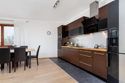 a kitchen with wooden cabinets and a table with chairs at Dzielnica XIII Podgórze Kraków by Noclegi Renters in Kraków