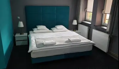 a bedroom with a large bed with a blue headboard at NATA Pokoje Gościnne Restauracja in Libiąż