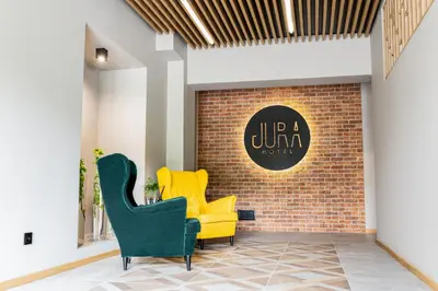 a lobby with two yellow chairs and a brick wall at Jura Hotel Osiek in Olkusz