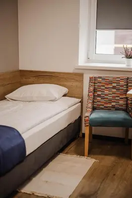 a bedroom with a bed and a chair and a window at Jura Hotel Osiek in Olkusz