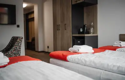 a room with three beds with red and white sheets at Jura Hotel Osiek in Olkusz