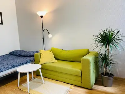 a living room with a green couch and a bed at Luxodonta Apartment in Kraków