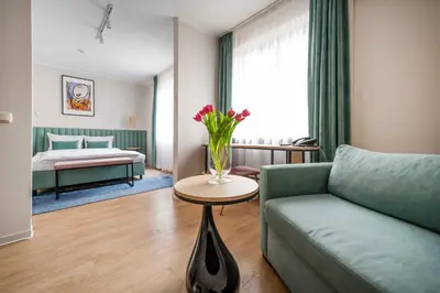 a living room with a couch and a vase of flowers on a table at Hotel H12**** in Kraków