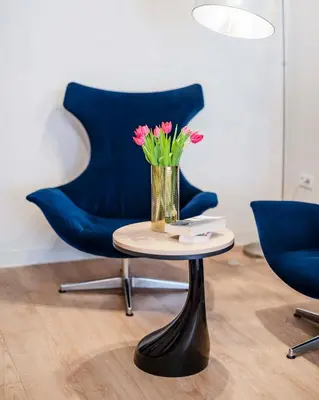 a vase of flowers on a table with a blue chair at Hotel H12**** in Kraków