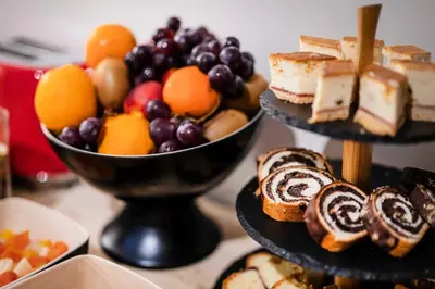 a table topped with a bowl of fruit and cakes at Hotel H12**** in Kraków