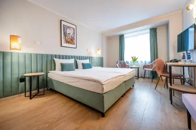 a hotel room with a bed and a table and chairs at Hotel H12**** in Kraków