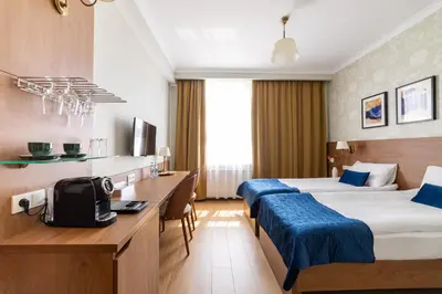 a hotel room with two beds and a desk at Portal House Apartments in Kraków