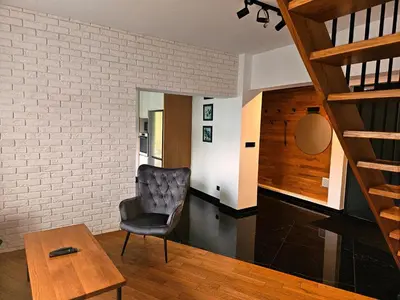 a living room with a staircase and a couch at Domek z jacuzzi Cztery Pory Roku in Czchów