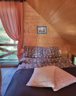 a bedroom with a bed in a wooden cabin at Domki na Górniej Łące - Domek Górny in Łazany