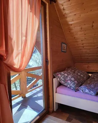 a small bed in a cabin with a large window at Domki na Górniej Łące - Domek Górny in Łazany