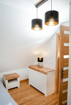 a bedroom with a bed and a table and two lights at Domki Łowisko Wieniec in Gdów