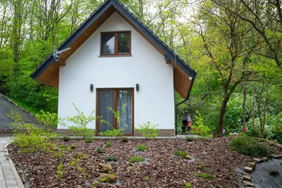 a small white house with a black roof at Domki Łowisko Wieniec in Gdów