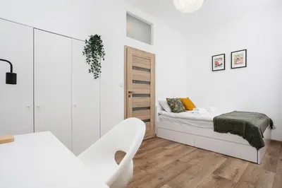 a white bedroom with a bed and a chair at Apartment à côté the train station - by Upstairs in Kraków