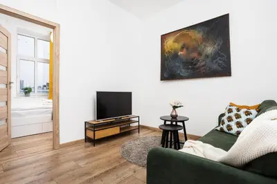 a living room with a green couch and a television at Apartment à côté the train station - by Upstairs in Kraków