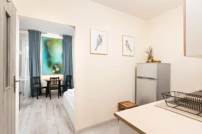 a white kitchen with a refrigerator and a table at Apartment à côté the train station - by Upstairs in Kraków
